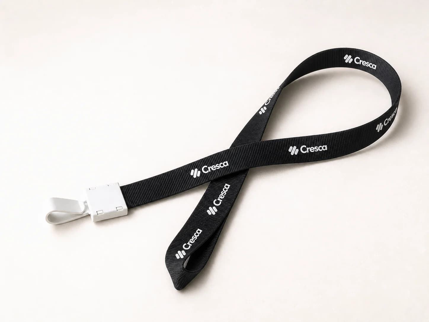 A black Cresca lanyard with a white clasp on a warm stone surface